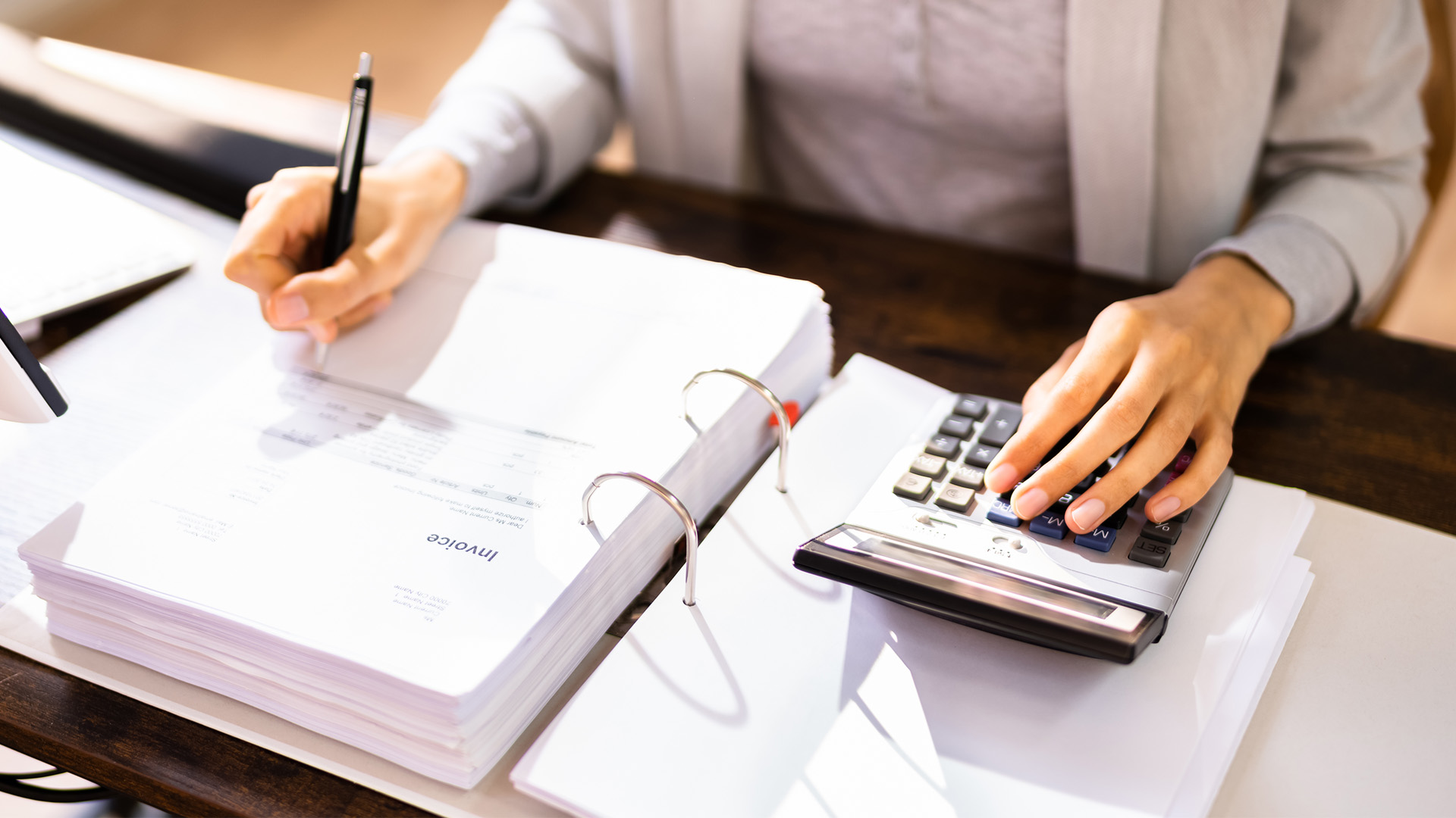 Person using a calculator and taking notes on tax documents, emphasizing tax preparation and audit avoidance strategies.