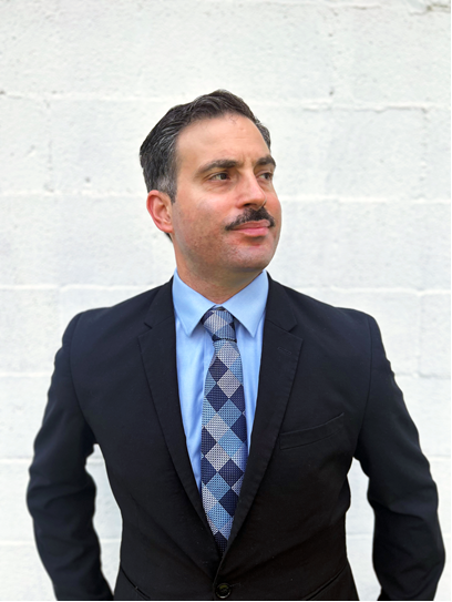 Professional attorney in a suit and tie, standing confidently against a neutral background, representing McCauley Law Offices' commitment to assisting clients with tax debt solutions.